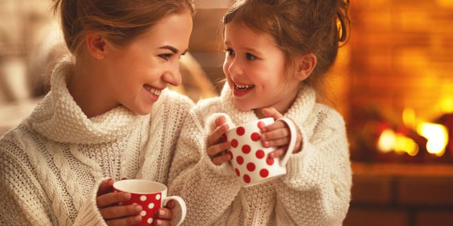 a mother and child drinking tea by the fireplace