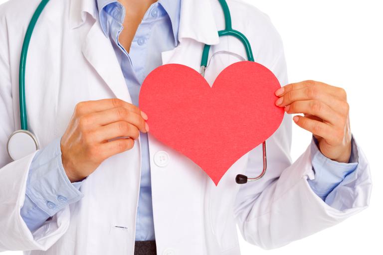 a doctor holding a paper cut-out of a heart